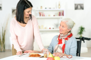 healthcare worker offering meal to elderly woman
