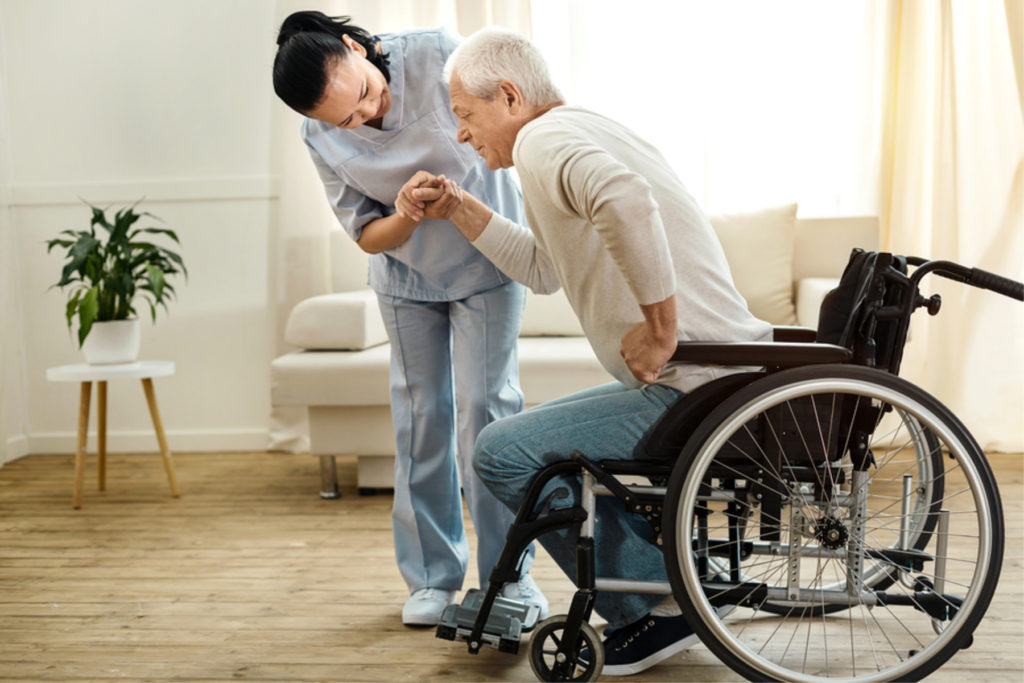 in-home caretaker helps elderly man in wheelchair